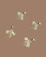 Capa de paño color rojo con corte amplio y caída natural. Presenta detalles de dijes metálicos en baño de oro distribuidos en la espalda y una etiqueta de cuero con el logo de la marca en la parte superior.