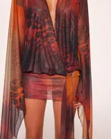 Minivestido cruzado con estampado animal print en tonos naranja, marrón y negro. Tiene escote en V pronunciado, mangas largas acampanadas y falda ajustada.