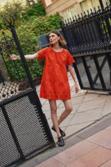 Vestido corto color naranja con bordados florales, corte holgado y mangas cortas.