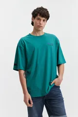 Remera verde esmeralda de manga corta con calce oversize, cuello redondo y estampado frontal con texto en azul.