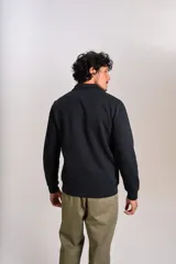 Buzo de cuello alto con cierre frontal parcial, manga larga y puños acanalados. Presenta un diseño liso en color negro con el logo de la marca bordado en el pecho.