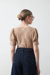 Remera negra de manga corta con textura floral en relieve. Presenta un diseño de inspiración romántica con mangas ligeramente abullonadas que aportan estructura y un ajuste al cuerpo.