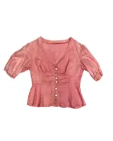 Camisa color mostaza de lino con corte en la cintura y abotonadura central. Tiene manga abullonada con detalle de elástico en puños.