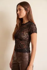 Remera de encaje negro al cuerpo, con mangas cortas y cuello redondo.