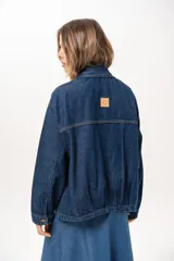 Campera de jean azul de silueta relajada, con cuello clásico, cierre frontal con cremallera metálica y bolsillos laterales.