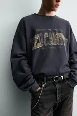 Sudadera de manga larga, cuello redondo y corte cropped, color azul marino oscuro con efecto lavado. Presenta un estampado frontal en tonos dorados y desgastados con el texto "RED CANYON" y las palabras "Granite" y "Majesty" flanqueando un símbolo de cruz.