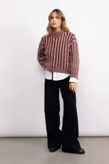 Sweater de tejido de punto con diseño de trenzas verticales, cuello alto y corte oversize. Presenta una textura marcada y puños acanalados.