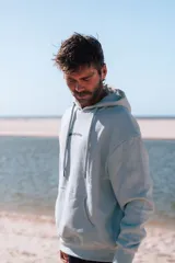 Hoodie celeste claro con capucha y estampado en la espalda que dice "glassy surfer RIDE YOUR OWN WAVE" en color azul oscuro.