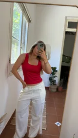 Pantalón de lino color crudo, de corte ancho y tiro alto, con pretina elastizada y tajos laterales en el ruedo.