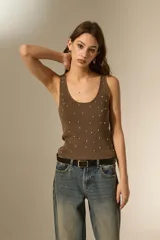 Musculosa de tejido de punto color marrón, con breteles anchos, cuello redondo y detalle de pequeñas cuentas metálicas distribuidas por toda la prenda.