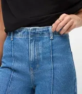 Pantalón de jean modelo wide leg cropped con cintura alta y sastre. Presenta costuras verticales frontales, bolsillos laterales y cierre delantero con botón y cremallera.