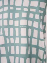 Conjunto de pijama de dos piezas, color verde menta con estampado de cuadros irregulares en blanco. Incluye camisa de manga larga con botones y pantalón largo con cintura elástica.