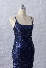 Vestido corto ajustado de tirantes finos, completamente cubierto de lentejuelas azul oscuro o violeta brillante.