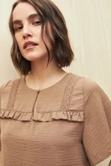 Blusa negra con textura, canesú con encaje, volados, corte fluido y mangas cortas amplias.