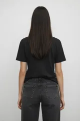 Remera de algodón color negro, de corte holgado y manga corta, con cuello a la base. Presenta un estampado frontal de una rana con sombrero vaquero y la frase 'hold on partner, im overstimulated'.