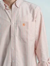 Camisa de corte regular confeccionada en tejido Oxford de algodón, con diseño de rayas verticales finas. Presenta cuello abotonado, cierre frontal con botones y un bolsillo en el pecho.