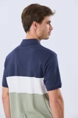 Remera polo de manga corta con diseño en bloques de color en tonos azul marino, blanco y verde militar, con bordado frontal y cierre de botones.