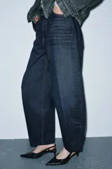 Jeans de tiro alto con corte barrel y diseño tapered, confeccionados en denim con efecto lavado y detalle de raya planchada. Presentan cintura con trabillas, cierre frontal con cremallera y botón, y bolsillos funcionales en delantero y espalda.