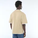 Camiseta color beige de manga corta con diseño efecto 2 en 1, presentando detalles blancos en el cuello redondo, los puños y el borde inferior.