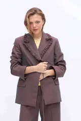 Blazer sastrero oversize color marrón con diseño de rayas diplomáticas. Cuenta con solapa con volados fruncidos, bolsillos con solapa en los laterales y cierre cruzado con lazo para atar en la cintura.