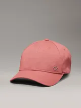 Gorra de béisbol color rosado, confeccionada en sarga de algodón orgánico, con cierre ajustable y herraje metálico con el monograma 'ck' en la parte frontal.