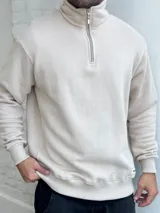 Buzo beige de felpa con cuello alto y cierre metálico a la mitad del torso.
