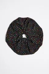 Coletero negro de tejido con cristales multicolores y placa metálica con logo.