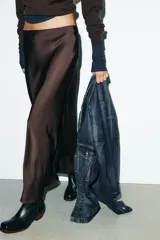 Falda midi negra de tejido satinado, corte recto y tiro alto con cintura elástica.