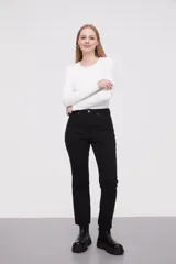 Pantalon jean de corte flare, tiro medio, con ruedo desflecado y cierre frontal con botón y cremallera.