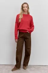 Sweater de punto de corte holgado, con cuello redondo y mangas largas con puños acanalados. Presenta un diseño liso en color rojo con un pequeño detalle de etiqueta en la manga.