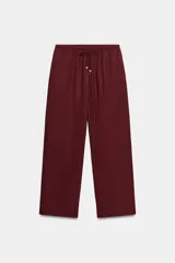 Pantalón de tiro medio y pernera recta con textura, de color marrón. Cuenta con cintura elástica y cordón ajustable con abalorios decorativos.