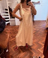 Vestido largo color champagne con brillo, de corte holgado y tajos laterales. Los breteles son anchos y están bordados a mano con detalle de cuero.