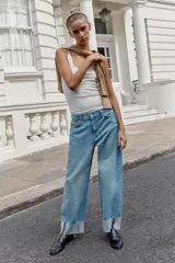 Jeans baggy de tiro medio con pernera holgada, diseño de cinco bolsillos y bajo acabado en vuelta. Cuenta con cintura elástica en la espalda y cierre frontal con cremallera y botón.