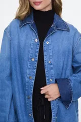 Camisa oversize de denim azul claro, con cuello clásico, mangas largas y cierre frontal de broches metálicos.