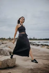 Pollera larga de tejido de punto color naranja con destellos brillantes, presenta un tajo frontal y una faja de ajuste en la cintura con lazo lateral.