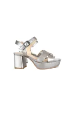 Sandalias de plataforma con taco cuadrado, confeccionadas en cuero metalizado color plateado. Presentan tiras cruzadas en el empeine y cierre con hebilla ajustable en el tobillo.