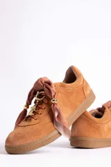 Zapatillas de gamuza color marrón con suela de goma color caramelo. Presentan cordones al tono y un detalle decorativo de pañuelo estampado atado en los laterales con esferas metálicas doradas.