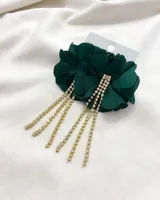 Aros colgantes con forma de flor de tela color verde esmeralda, con flecos de strass dorados.