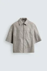 Sobrecamisa de manga corta efecto piel de corte relajado, color gris, con cuello solapa, bolsillo de parche en el pecho y cierre frontal con cremallera.