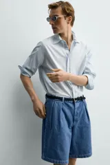 Bermuda de denim de algodón con corte relaxed fit, cintura con pliegues dobles en el delantero, bolsillos laterales y traseros de doble vivo, con efecto lavado y cierre frontal con cremallera y botón.