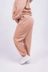 Pantalón de jogging gris oscuro, de corte holgado con cintura elástica y puños ajustados en los tobillos. Presenta bolsillos laterales y un pequeño logo bordado en la pierna izquierda.