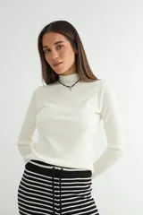 Polera de tejido de punto acanalado, color blanco, con cuello alto y mangas largas.