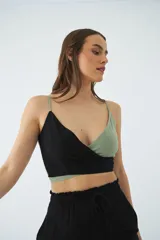 Blusa corta tipo top con diseño cruzado en escote en V, confeccionada en combinación de colores negro y verde. Presenta tirantes finos ajustables y detalle de grifa de cuero.