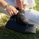 Botas cortas de cuero negro con plataforma y cuatro hebillas metálicas laterales.