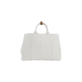 Cartera Prada tipo shopper de lona color beige claro, con asas superiores, detalles de cuero marrón y correa de hombro ajustable con el logo de la marca bordado. Cuenta con el nombre y logo de Prada bordados en el frente y un llavero colgante de cuero.