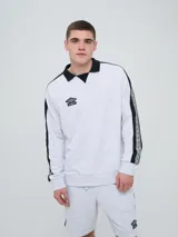Buzo deportivo Umbro modelo Mixtape color gris melange, con cuello polo negro y cierre frontal parcial. Presenta bandas laterales negras en las mangas con estampado gráfico de rombos y el logo de la marca bordado en el pecho.