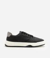 Championes urbanos estilo skate de color negro con suela bicolor blanca y negra, talón gris y detalles perforados en la puntera.