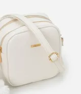 Cartera bandolera Satinato pequeña de color blanco, de diseño estructurado con textura floater, cierre de cremallera y detalles metálicos dorados. Incluye una correa larga ajustable y un pompón decorativo colgante.