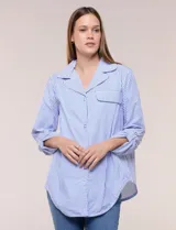 Sobrecamisa holgada de algodón liviano, con estampado de rayas verticales en tonos azul y blanco, diseño oversize, cuello solapa, mangas largas ajustables con presilla y ruedo curvo.