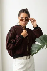 Campera tipo bomber de gamuza con estampado animal print en tonos bordó y negro. Presenta cierre frontal dorado, puños y cintura elástica en color negro, y detalle de franjas laterales en las mangas.